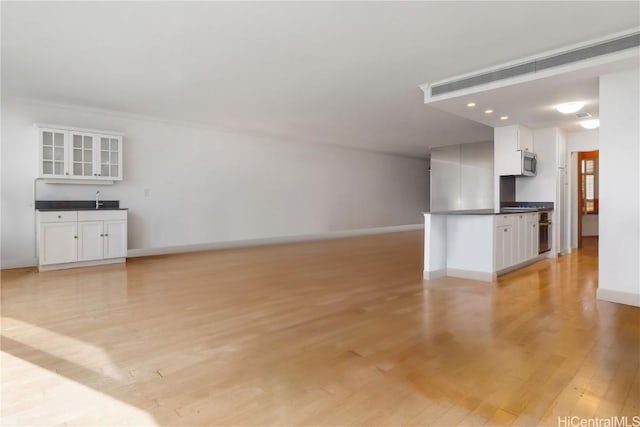 unfurnished living room with bar area and light hardwood / wood-style floors