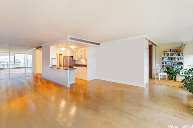 unfurnished living room with ornamental molding, expansive windows, and light wood-type flooring