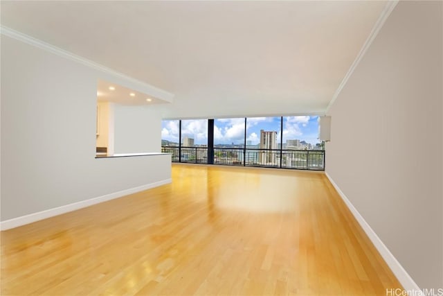 empty room featuring expansive windows, ornamental molding, and hardwood / wood-style floors