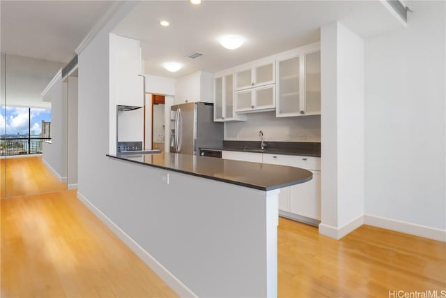 kitchen featuring stainless steel fridge with ice dispenser, white cabinetry, sink, light hardwood / wood-style floors, and kitchen peninsula