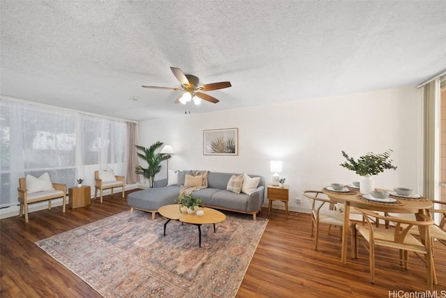 living room featuring dark wood-type flooring, ceiling fan, and a textured ceiling