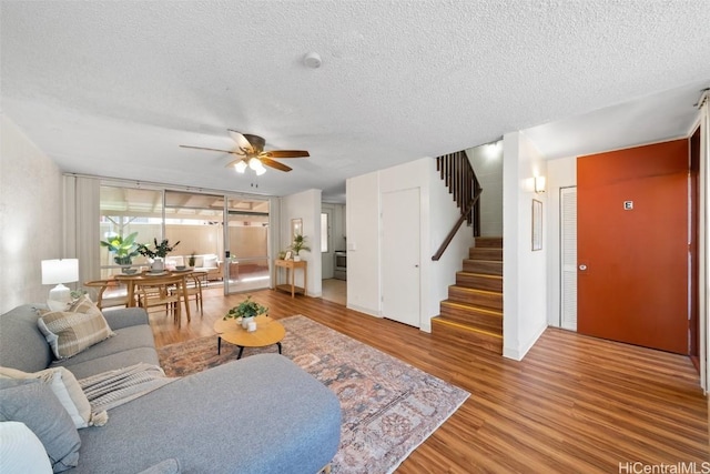 living room with ceiling fan, hardwood / wood-style flooring, and a textured ceiling