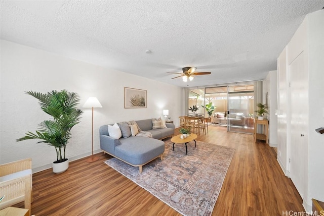 living room featuring ceiling fan, hardwood / wood-style floors, and a textured ceiling