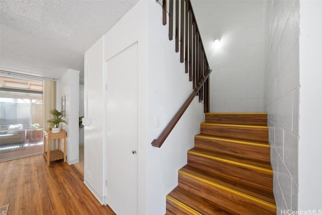 stairway with hardwood / wood-style flooring and a textured ceiling