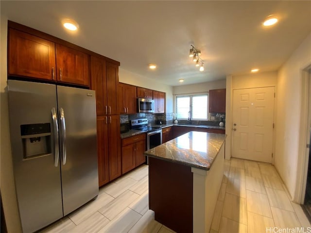 kitchen featuring sink, appliances with stainless steel finishes, a center island, tasteful backsplash, and stone countertops