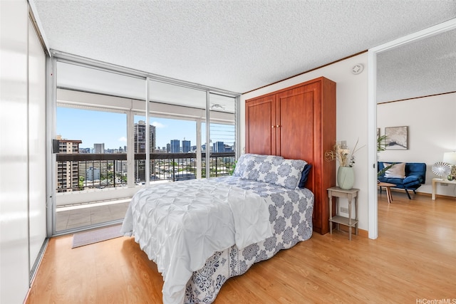 775 Kinalau Pl Unit 1907, Honolulu, HI 96813 - bedroom featuring light wood-style flooring, access to outside, a textured ceiling, and a skyline view