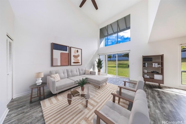 living area with high vaulted ceiling, ceiling fan, baseboards, and wood finished floors