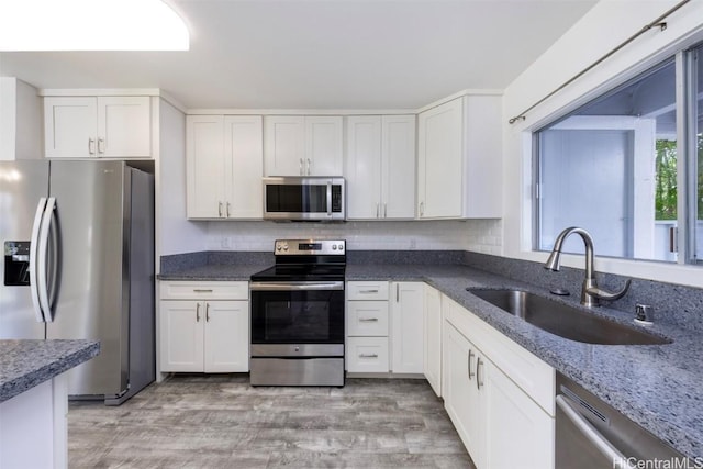 kitchen with stainless steel appliances, backsplash, a sink, and white cabinetry