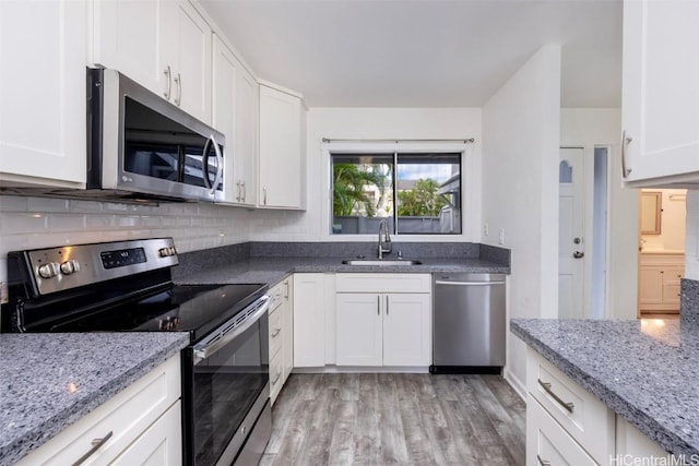 kitchen featuring appliances with stainless steel finishes, a sink, light stone counters, and white cabinets