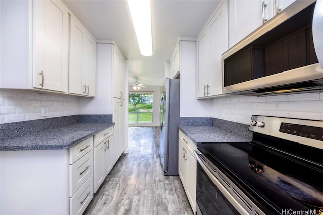 kitchen with appliances with stainless steel finishes, white cabinets, decorative backsplash, ceiling fan, and light hardwood / wood-style floors