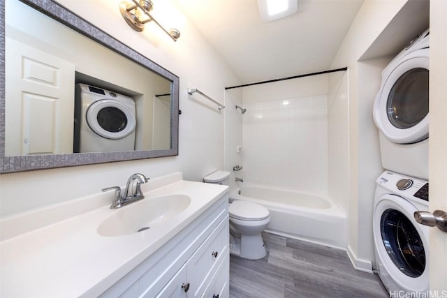 bathroom featuring stacked washer and clothes dryer, toilet, tub / shower combination, vanity, and wood finished floors