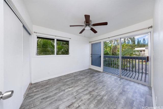 spare room with ceiling fan, plenty of natural light, wood finished floors, and baseboards