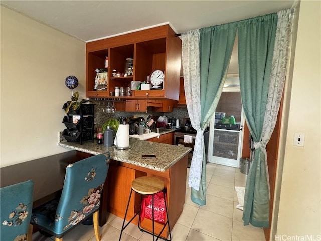 bar with light stone counters, light tile patterned floors, decorative backsplash, and sink