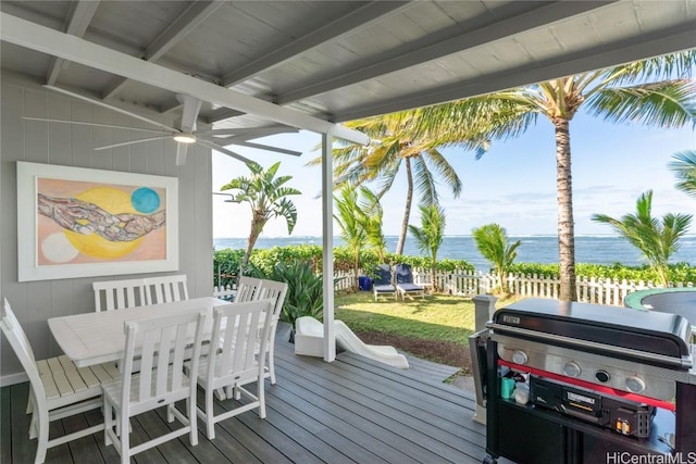 wooden terrace featuring grilling area, a lawn, ceiling fan, and a water view