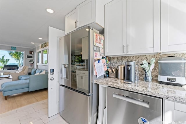 kitchen with light stone countertops, white cabinetry, appliances with stainless steel finishes, and tasteful backsplash