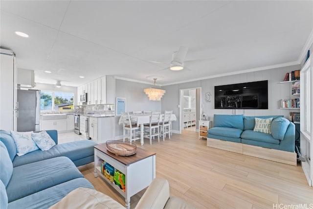 living room featuring crown molding, light hardwood / wood-style floors, and ceiling fan with notable chandelier