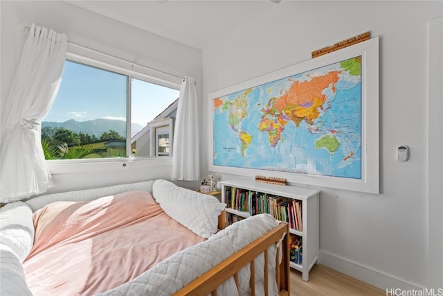 bedroom with a mountain view and light hardwood / wood-style flooring