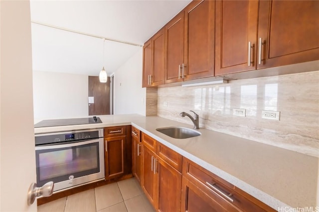 kitchen featuring pendant lighting, sink, decorative backsplash, stainless steel oven, and black electric cooktop