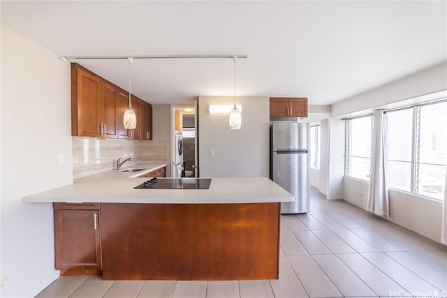 kitchen featuring stainless steel refrigerator, black electric stovetop, kitchen peninsula, and hanging light fixtures