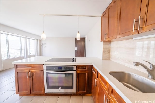 kitchen featuring hanging light fixtures, stainless steel oven, and kitchen peninsula