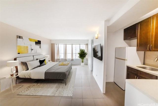 bedroom featuring white refrigerator, light tile patterned flooring, and sink