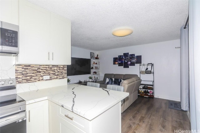 kitchen with white cabinetry, light stone countertops, appliances with stainless steel finishes, and kitchen peninsula