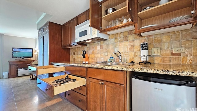 kitchen featuring dark tile patterned floors, refrigerator, sink, and backsplash