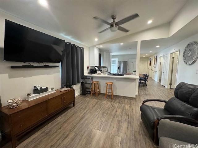 living room with ceiling fan, light hardwood / wood-style floors, and vaulted ceiling