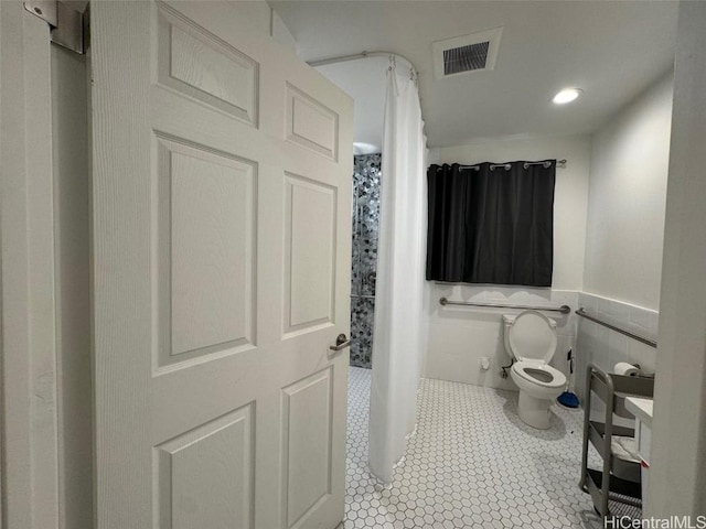 bathroom with tile patterned floors, toilet, a shower with shower curtain, and tile walls