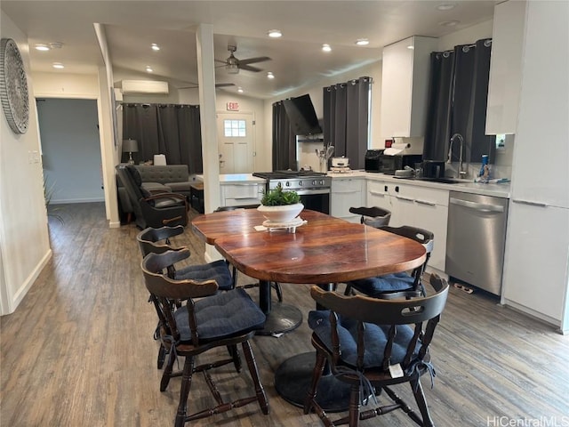 dining space with sink, light hardwood / wood-style floors, a wall mounted AC, and ceiling fan