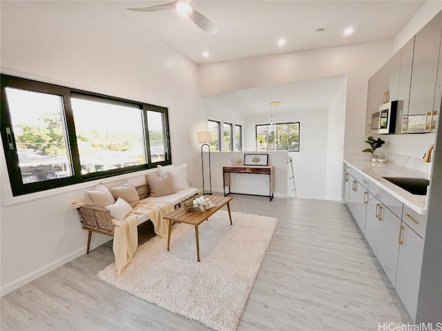 living room featuring ceiling fan, sink, and light hardwood / wood-style floors