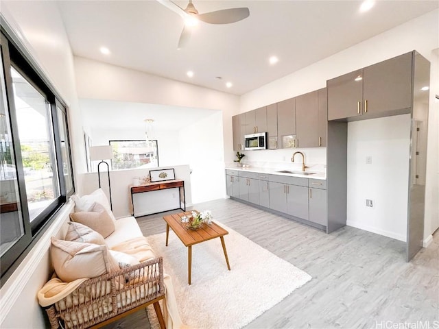 living room featuring sink, light hardwood / wood-style flooring, and ceiling fan