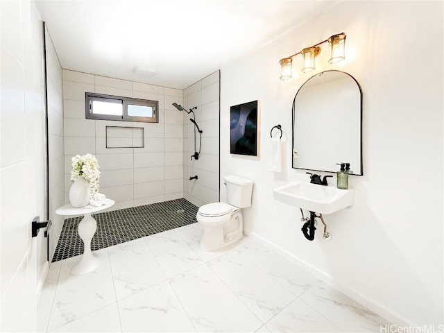 bathroom with toilet, sink, and a tile shower