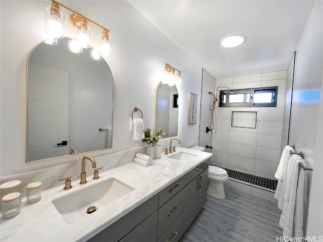 bathroom featuring vanity, toilet, and a tile shower