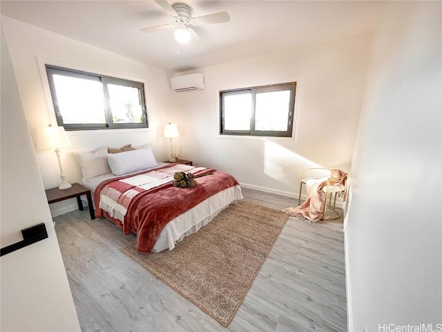 bedroom with multiple windows, ceiling fan, a wall mounted AC, and light wood-type flooring