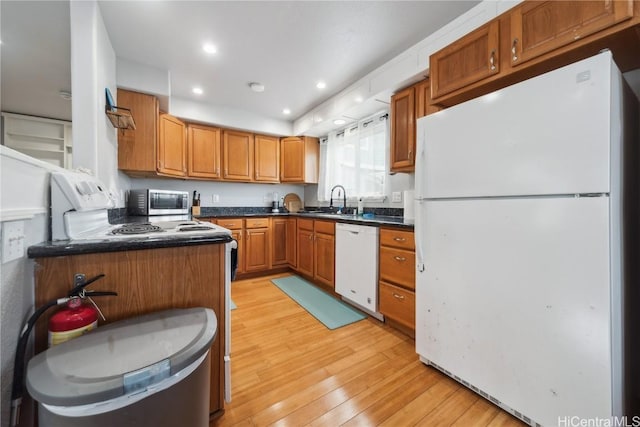 kitchen with sink, white appliances, light hardwood / wood-style flooring, and kitchen peninsula