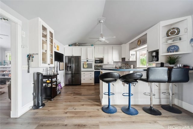 kitchen with a kitchen bar, light hardwood / wood-style flooring, refrigerator with ice dispenser, oven, and white cabinets