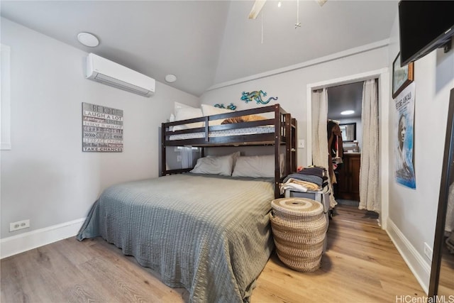 bedroom with a wall mounted air conditioner, vaulted ceiling, and hardwood / wood-style floors