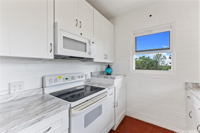 kitchen with white cabinetry, light stone countertops, and white appliances