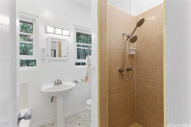 bathroom with a tile shower and toilet