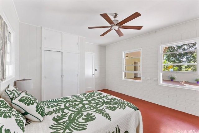 bedroom featuring a closet, ceiling fan, and brick wall