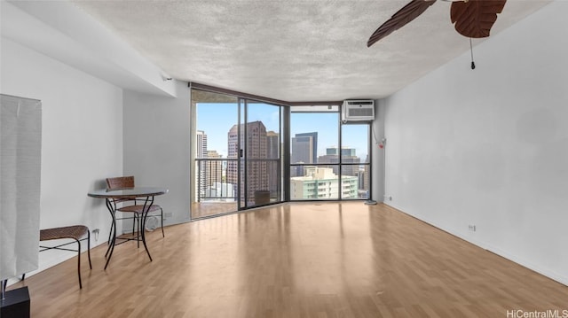 empty room with hardwood / wood-style flooring, expansive windows, and a textured ceiling