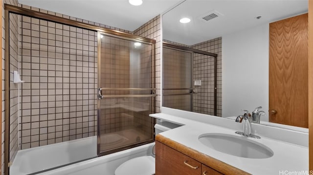 full bathroom featuring vanity, shower / bath combination with glass door, and toilet