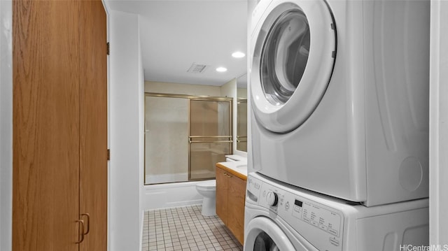 laundry area with stacked washer and clothes dryer and light tile patterned flooring