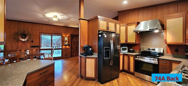 74 Makaweo Ave, Wahiawa, HI 96786 - kitchen featuring light wood-style flooring, wooden walls, wall chimney range hood, black fridge, and stainless steel range with electric stovetop
