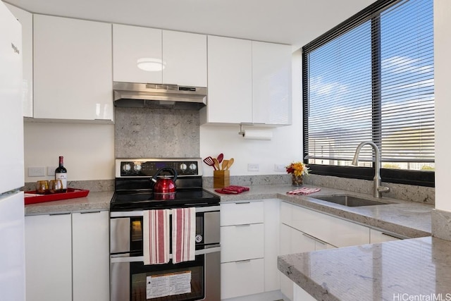 kitchen featuring light stone counters, double oven range, sink, and white cabinets