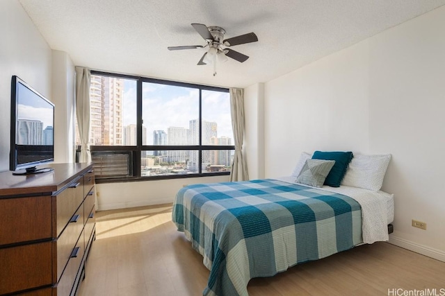 bedroom with ceiling fan, a textured ceiling, and light wood-type flooring