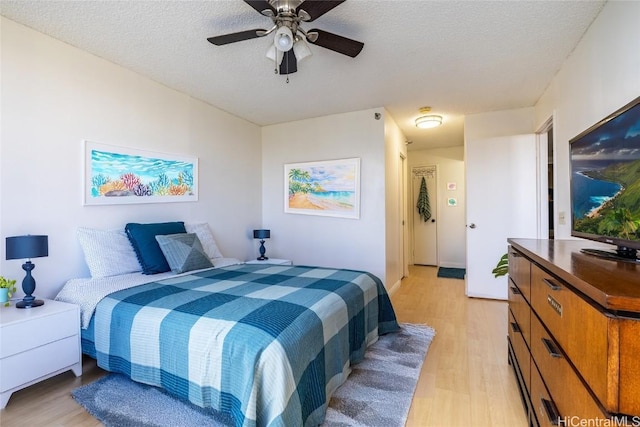 bedroom featuring ceiling fan, light hardwood / wood-style floors, and a textured ceiling