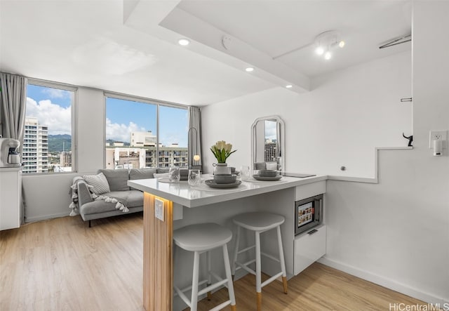 kitchen featuring plenty of natural light, a kitchen breakfast bar, kitchen peninsula, and light wood-type flooring