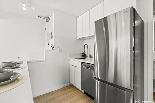 kitchen with white cabinetry, stainless steel appliances, light hardwood / wood-style floors, and sink